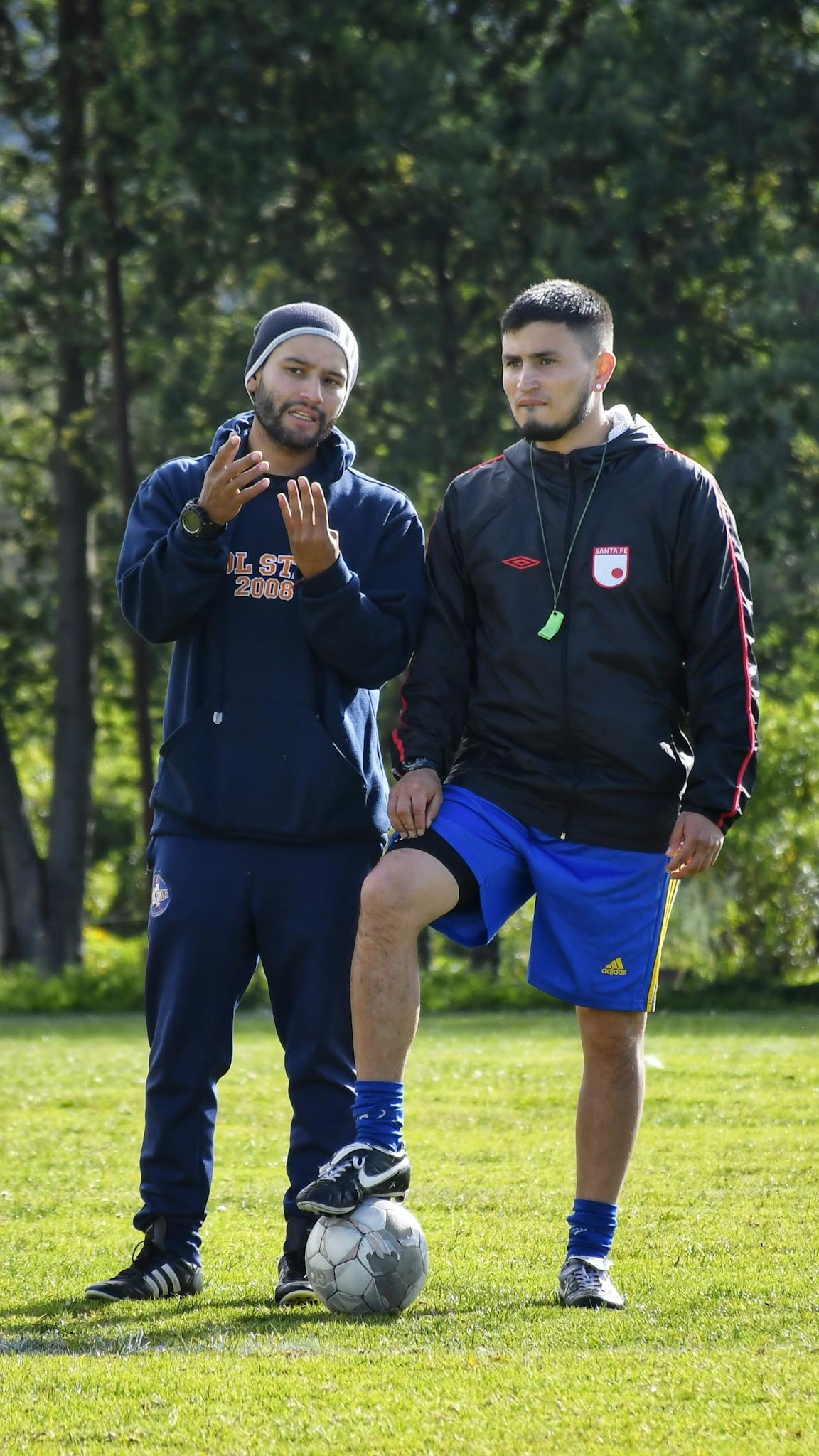 Soccer coach discussing strategy with player on a sunny field.
